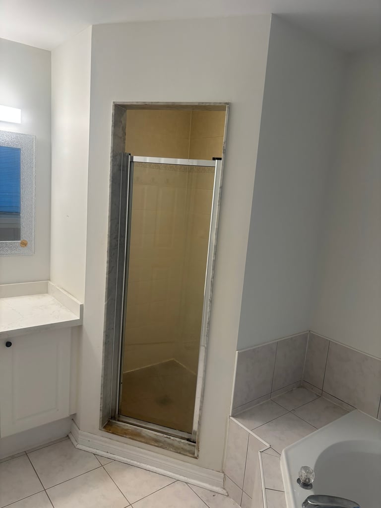 Bathroom interior with shower enclosure, toilet, sink, and white tile flooring
