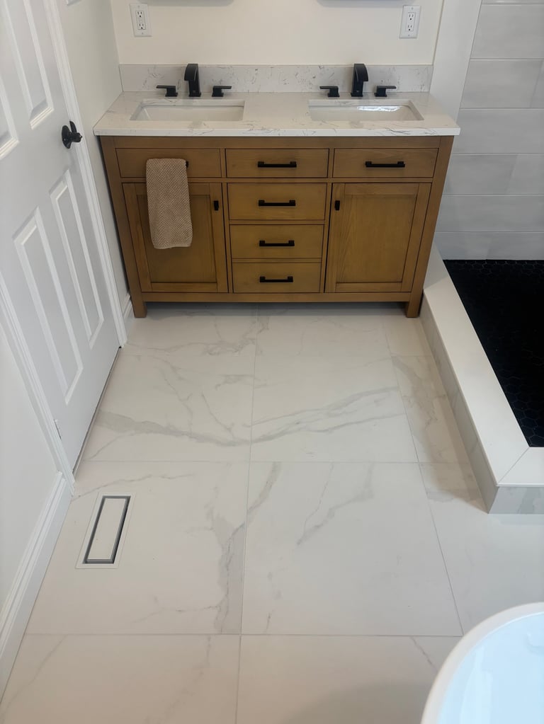 Bathroom with double vanity featuring wood cabinetry, white countertop, and marble-pattern tile flooring